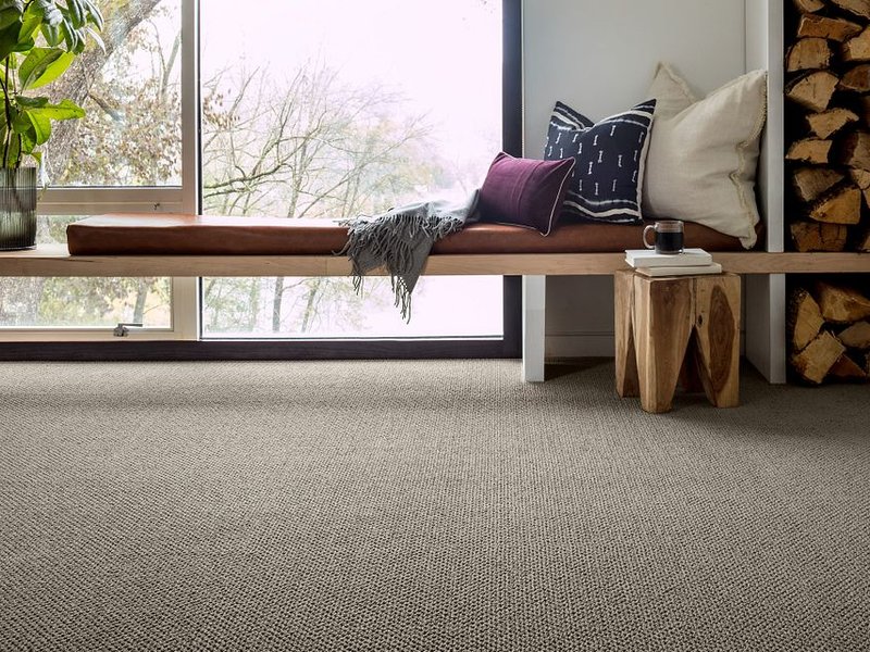 relaxing interior bench with a nice view from window in a living room with brown carpet from Carolina Flooring and Interiors in Grandy, NC area