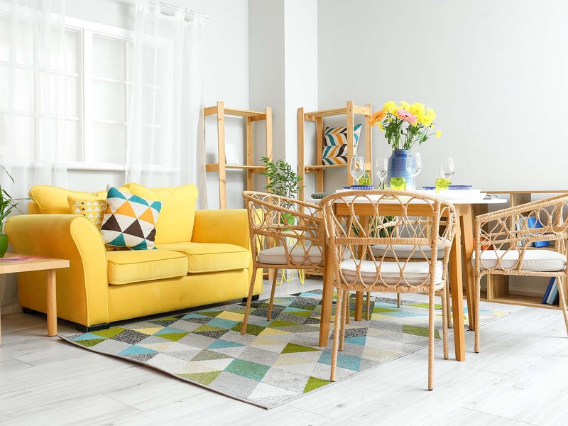 yellow couch and brown chairs and coffee table on a colorful patterned area rug from Carolina Flooring and Interiors in Grandy, NC area